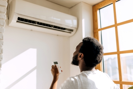 Young man turning on a mini split air conditioner.