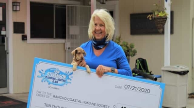 Lady Holding Check from John Stevenson to Rancho Coastal Humane Society Photo